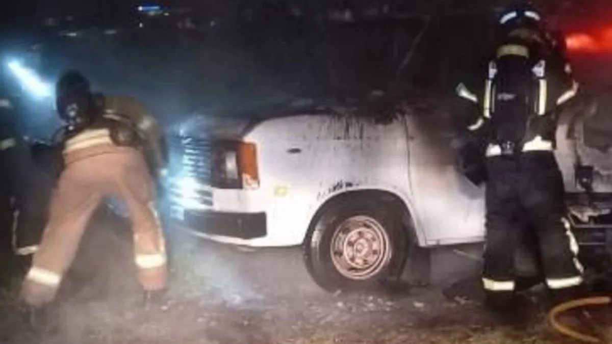 Foto de archivo de una caravana quemada y los bomberos actuando sobre ella